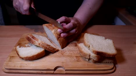 Cutting-homemade-bread-with-a-knife-on-wooden-table
