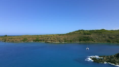 Coast-and-ocean-aerial-panorama,-single-catamaran-boat,-paradise-vacation