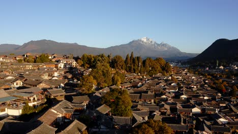 Aerial:-amazing-Lijiang-city-in-China,-Jade-Dragon-Mountain-backdrop