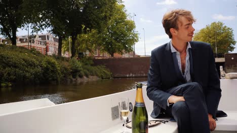 Young-guy-with-mustache-relaxing-on-white-boat-in-Amsterdam-canals