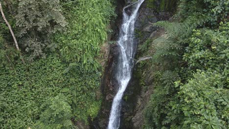 Pan-down-shot-of-lush-jungle-waterfall-with-tropical-vegetation-surrounding