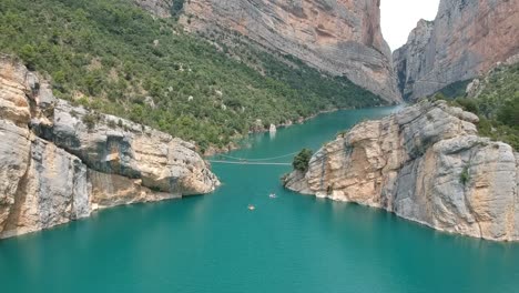 Aerial-views-of-the-Mont-Rebei-canyon-with-the-cliffs,-stairs-on-the-walls,-the-lake,-and-the-path-along-the-canyon