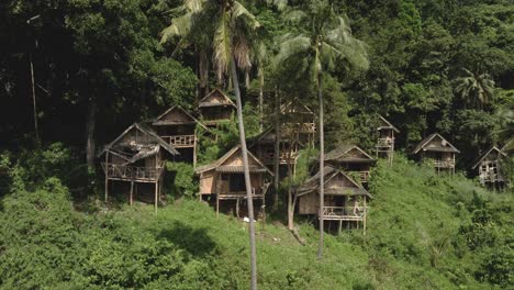 Pan-up-shot-of-ramshackle-bamboo-backpacker-huts-on-a-hill-in-the-jungle-in-Thailand