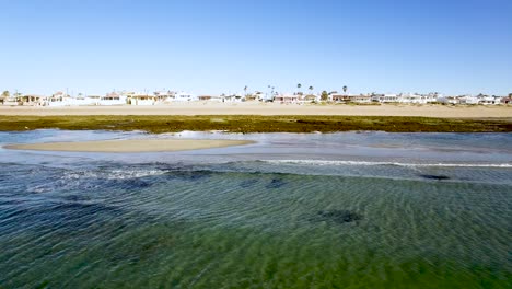 Aerial-pan-across-incoming-waves-at-low-tide,-Rocky-Point,-Puerto-Peñasco,-Gulf-of-California,-Mexico