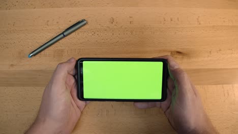 A-person-holding-a-phone-with-a-greenscreen-display