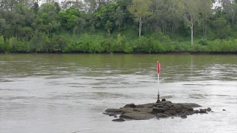 Channel-marker-on-rocks-in-this-Australian-outback-river,-flowing-through-the-rainforest-and-jungle
