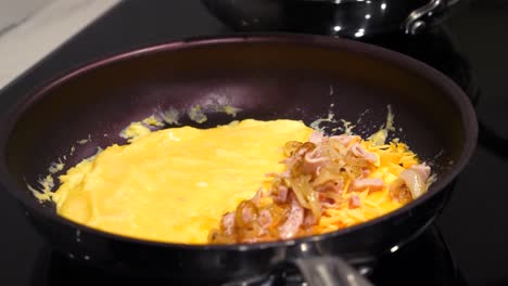 Spatula-Adding-Cooked-Ham-and-Onions-to-Egg-Omelet---Stovetop-Cooking