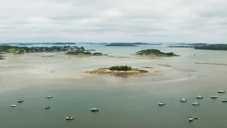 Aerial-view-of-a-coastal-new-england-harbor-revealing-islands,-watercraft-and-city-in-the-distance