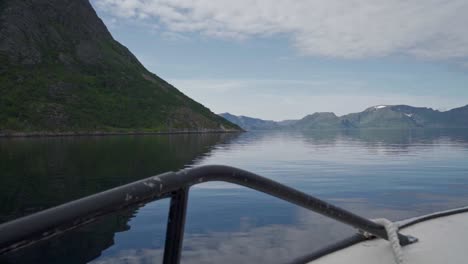 Sailing-Watercraft-Through-Pristine-River-With-Mountainous-Landscape-At-Background-In-Norway