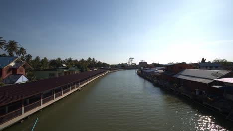 Calm-river-gently-flowing-through-a-village-in-Thailand-on-a-bright-sunny-day