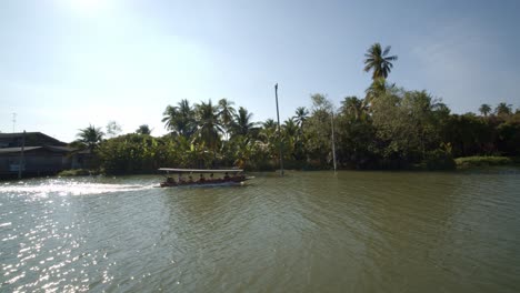 Un-Bote-De-Taxi-O-Ferry-Deslizándose-A-Lo-Largo-De-Un-Río-Tranquilo-A-Través-De-Un-Pueblo-En-Tailandia
