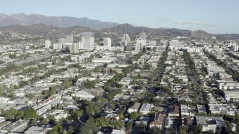 Aerial-rising,-City-of-Glendale-over-buildings-and-houses,-mountains-in-background,-clear-sunny-afternoon