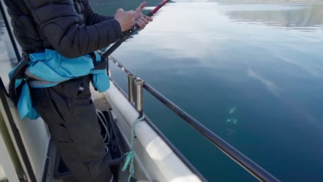 Mann-Auf-Dem-Boot,-Der-Angelrute-Aufrollt-Und-Zwei-Fische-Aus-Einem-See-In-Norwegen-Fängt
