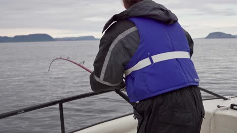 Pescador-Noruego-Con-Una-Caña-Pescando-Desde-El-Barco-En-Mar-Abierto-En-Noruega---Plano-Medio