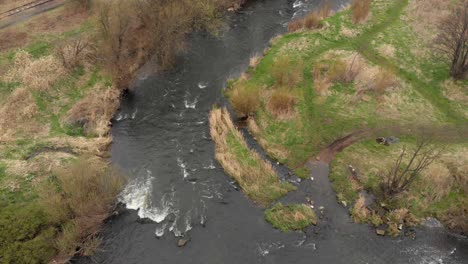 Aerial-view-of-a-fast-running-weir-flowing-downstream-with-grassy-banks-and-trees
