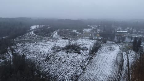 Drone-flyover-snowy-winter-landscape,-fields-and-lake-Sweden