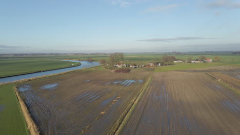 Aerial-of-muddy-meadows-near-a-small-farm