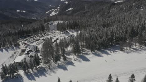 Kope-winter-resort-and-car-parking-lot-in-the-Pohorje-mountains-in-Slovenia,-Aerial-flyover-shot