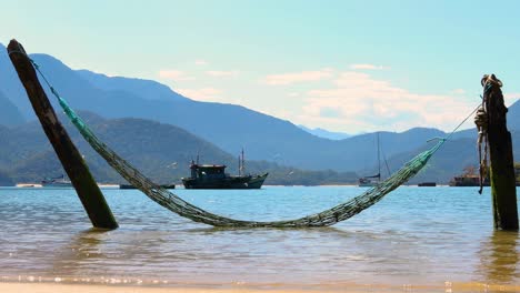 static-Hammock-in-the-water-with-peaceful-sea-background-with-fishing-boat-with-birds-flying