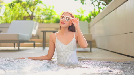 Asian-woman-with-sunglasses-relaxes-in-hydromassage-jacuzzi-pool