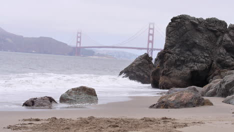 Slow-Waves-Crash-Repeatedly-on-an-Empty-Beach,-Foggy-Day,-Golden-Gate-Bridge