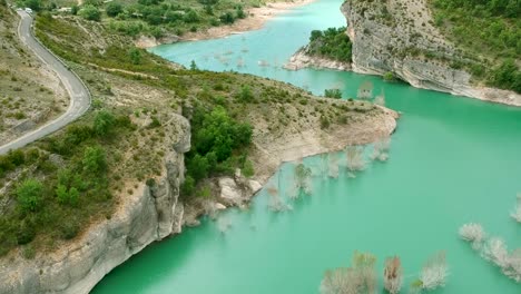 Rough-road-passing-along-water-reservoir-in-Catalonia-Spain
