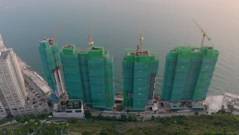 Construction-site-near-water-during-the-day,-view-from-a-drone