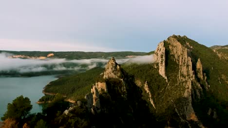 Clouds-covering-mountain-ranges,-water-flow-on-foot-of-mountain-Spain,-drone-view-of-mountain-ranges