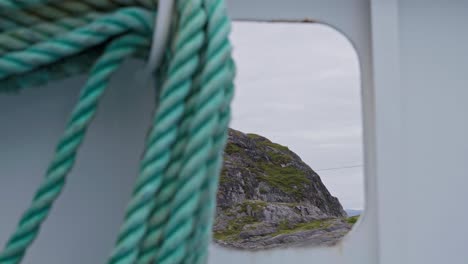 Detalle-De-Una-Cuerda-Sinuosa-En-Un-Barco-Con-Montañas-Al-Fondo-En-Noruega