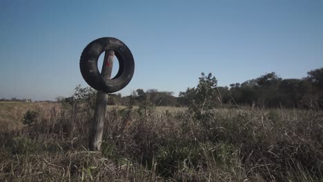 Static-shot-of-tire-placed-on-wooden-pole-as-entrance-sign-to-farm,-Argentina