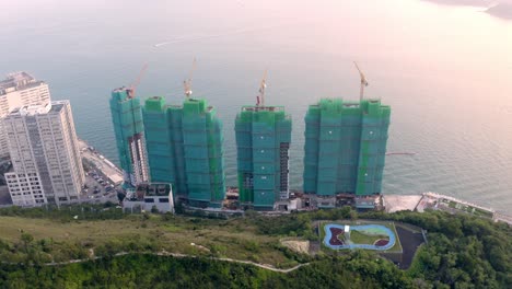 Construction-site-on-a-shore-near-water-during-the-day,-view-from-a-drone