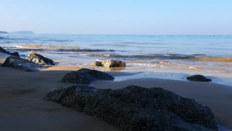 Handheld-low-angle-shot-of-small-waves-over-Rocks-on-beautiful-deserted-tropical-beach