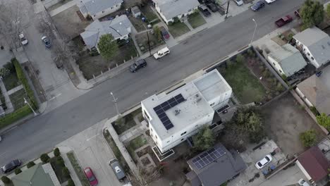 Rising-aerial-view-above-American-suburban-residential-building-with-solar-panel-alternative-energy-installation-on-rooftop