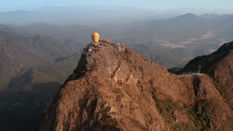 Rise-up-over-the-top-of-the-mountain-with-numerous-tourists-on-top,-with-mountain-ridge-in-background-in-afternoon