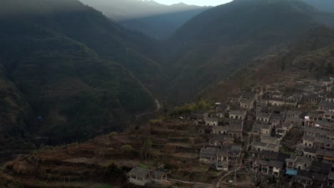 Fly-over-Ancient-Chinese-village-located-on-the-shadow-side-of-the-mountain-in-the-evening