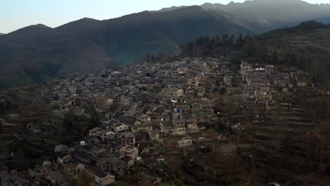 Fly-over-Ancient-Chinese-village-located-on-the-shadow-side-of-the-mountain-in-the-evening