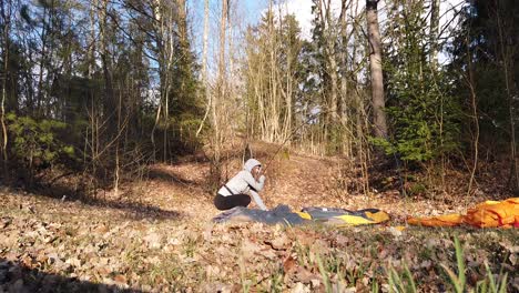 Female-Camper-Building-Up-A-Tent-Alone-In-The-Forest---wide-shot,-static