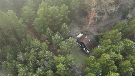 Beautiful-aerial-shot-over-remote-rural-cabin-house-in-dense-foggy-woods-from-above
