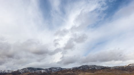 Two-layers-of-clouds-moving-in-separate-directions-over-the-snow-capped-Tehachapi-mountains---static-time-lapse