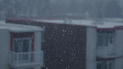 Focus-on-Slow-Motion-Winter-Snow-Falling-with-Exterior-Building-in-Background