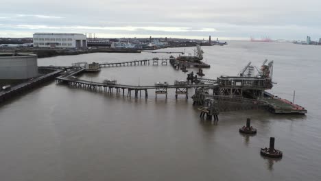 Drone-view-Tranmere-oil-terminal-Birkenhead-coastal-petrochemical-harbour-distribution-low-orbit-across-crane-pontoon
