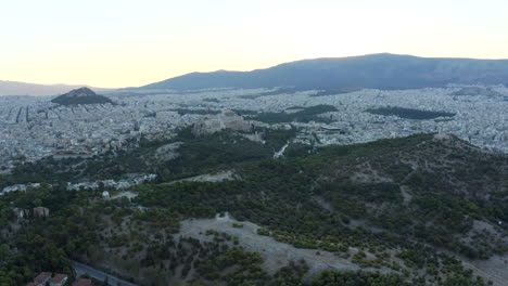 Wide-drone-aerial-shot-of-the-city-of-Athens-and-green-park-space-with-Acropolis-and-central-city-in-view,-Greece