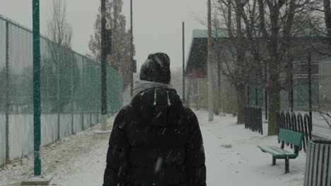 Mujer-Con-Abrigo-Negro-Camina-Por-Un-Sendero-Vacío-Del-Parque-De-Nieve