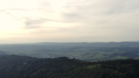 Rising-aerial-of-green-hills-and-distant-rural-town-in-Czech-Republic