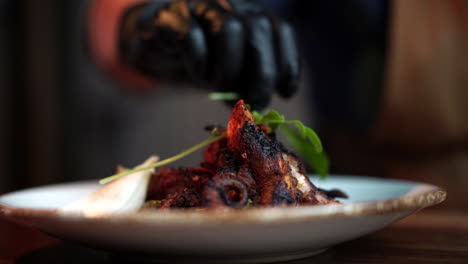 Chef-with-gloves-mounting-octopus-plate-with-garnish-slow-motion