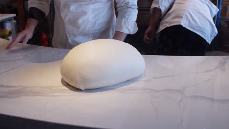 Chef-kneads-the-pizza-dough-on-the-kitchen-table-in-a-restaurant