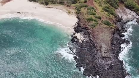 Drone-aerial-over-cliff-white-sand-blue-water-beach
