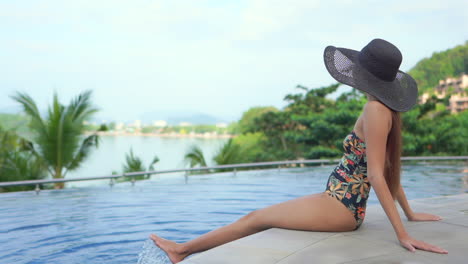 Attractive-Rich-Asian-Woman-in-Swimsuit-Sitting-on-Poolsie-on-Tropical-Holiday