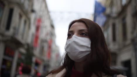 Beautiful-girl-wearing-protective-medical-mask-and-fashionable-clothes-stands-at-street