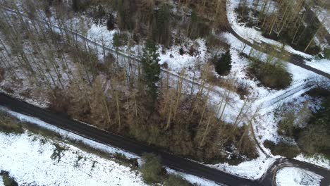 Snowy-rural-hazardous-remote-forest-road-aerial-snow-covered-woodland-birdseye-dolly-right